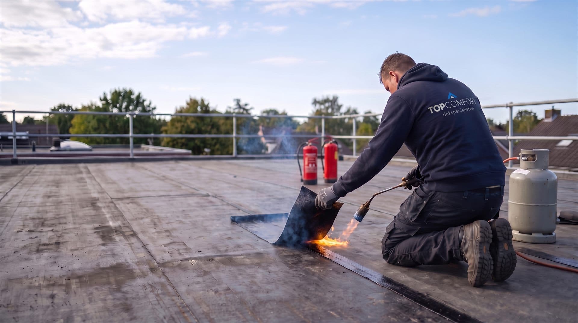 Dakdekker brandt bitumineuze dakbedekking aan op een plat dak tijdens een renovatie